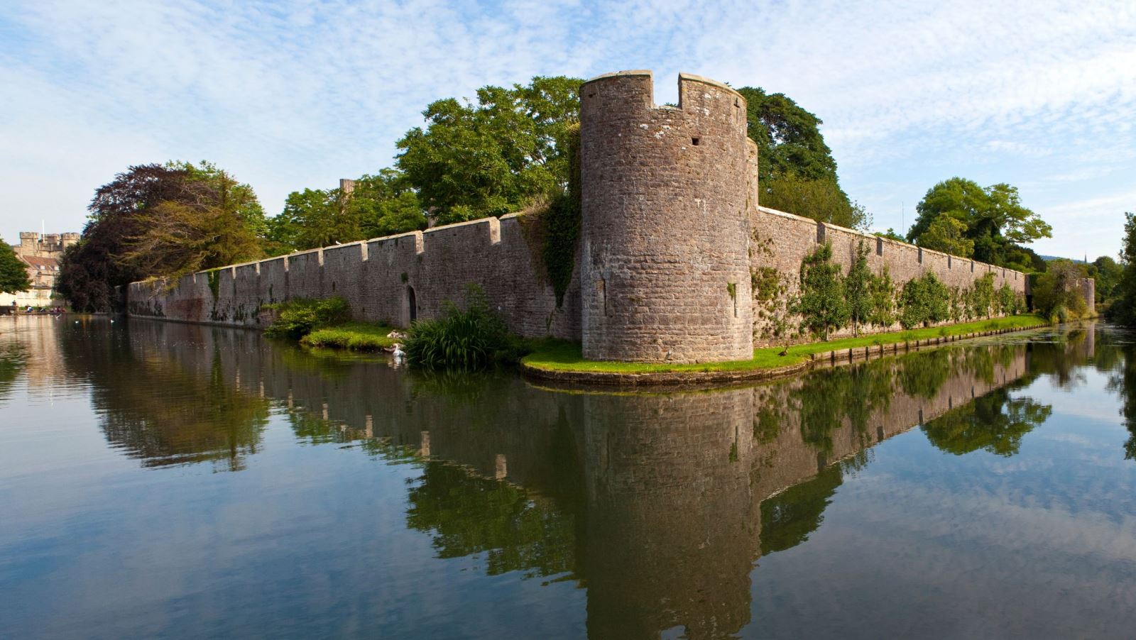 A large moat around a turret and a big stone palace wall